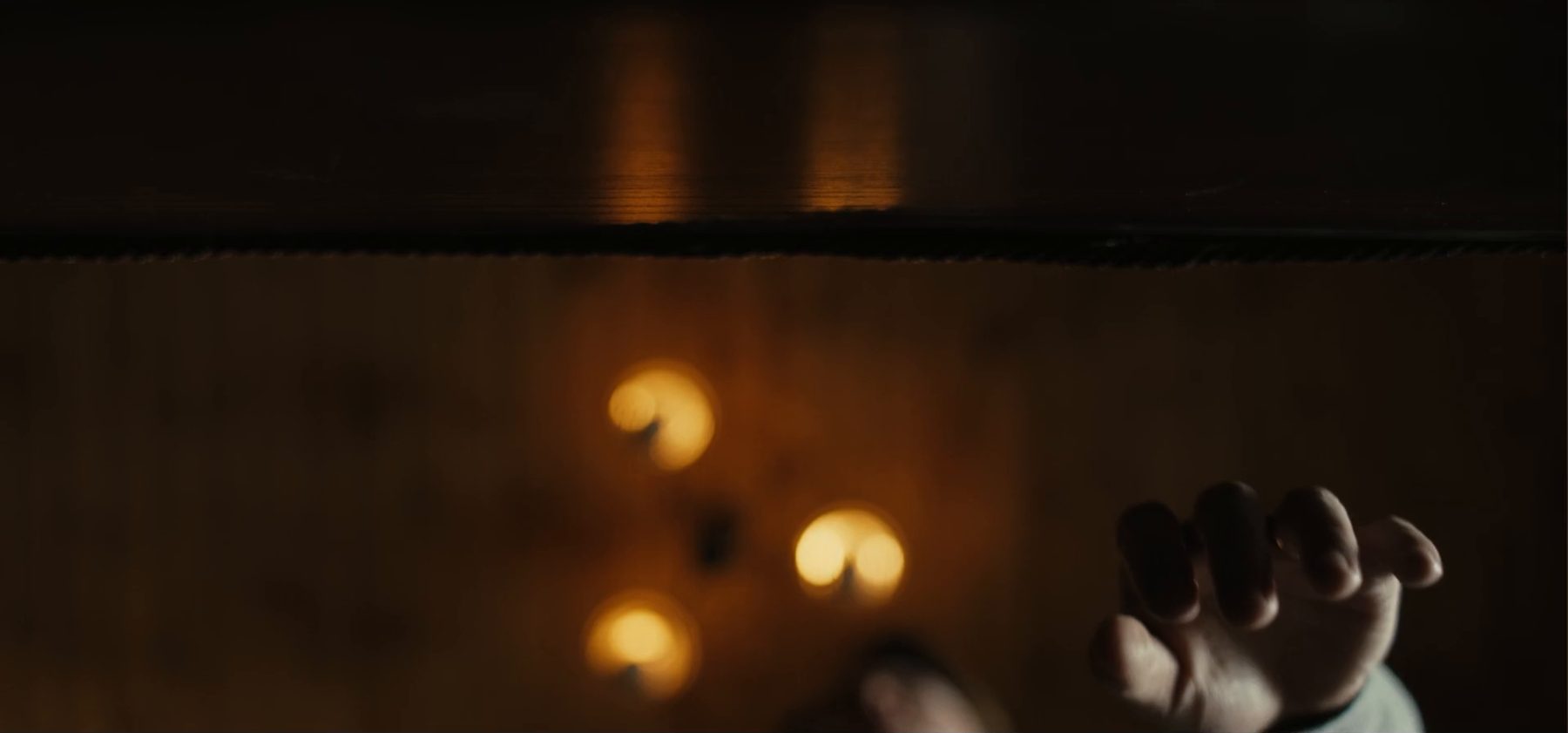 A hand reaching out among guttering candles