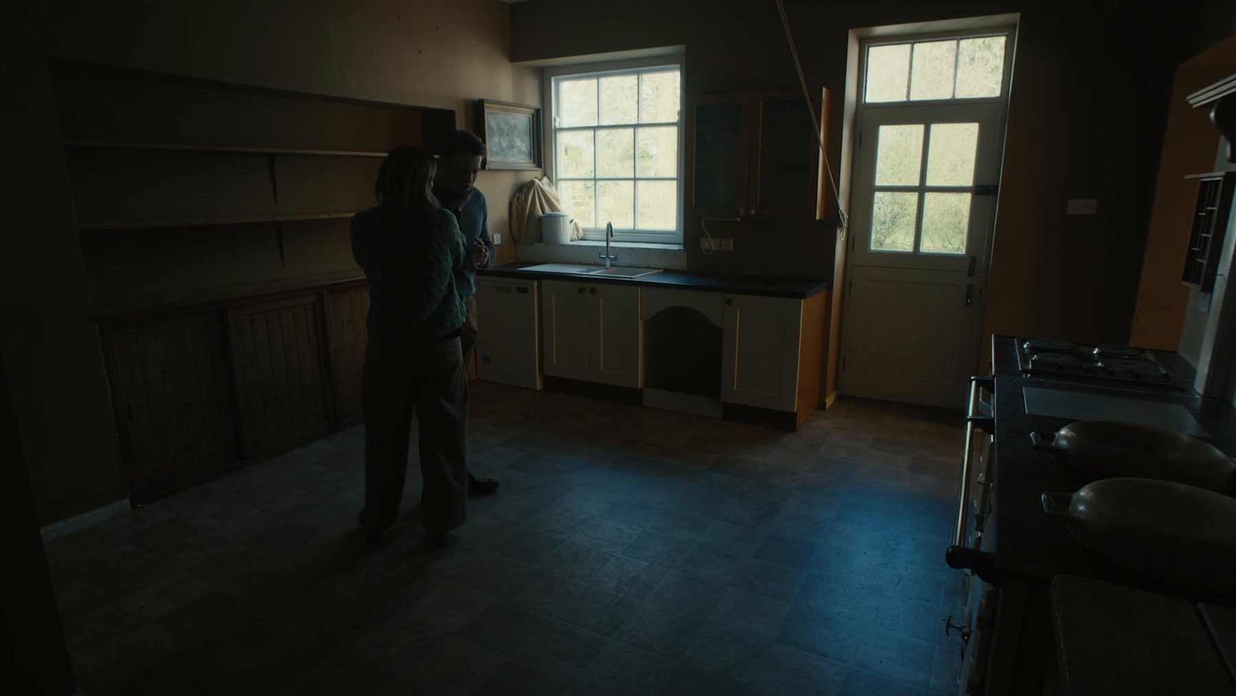 Two figures in a dark kitchen