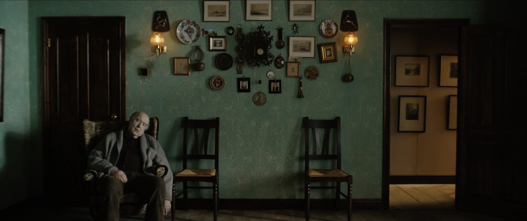 Grandfather alone in the green sitting room, empty chairs along the wall